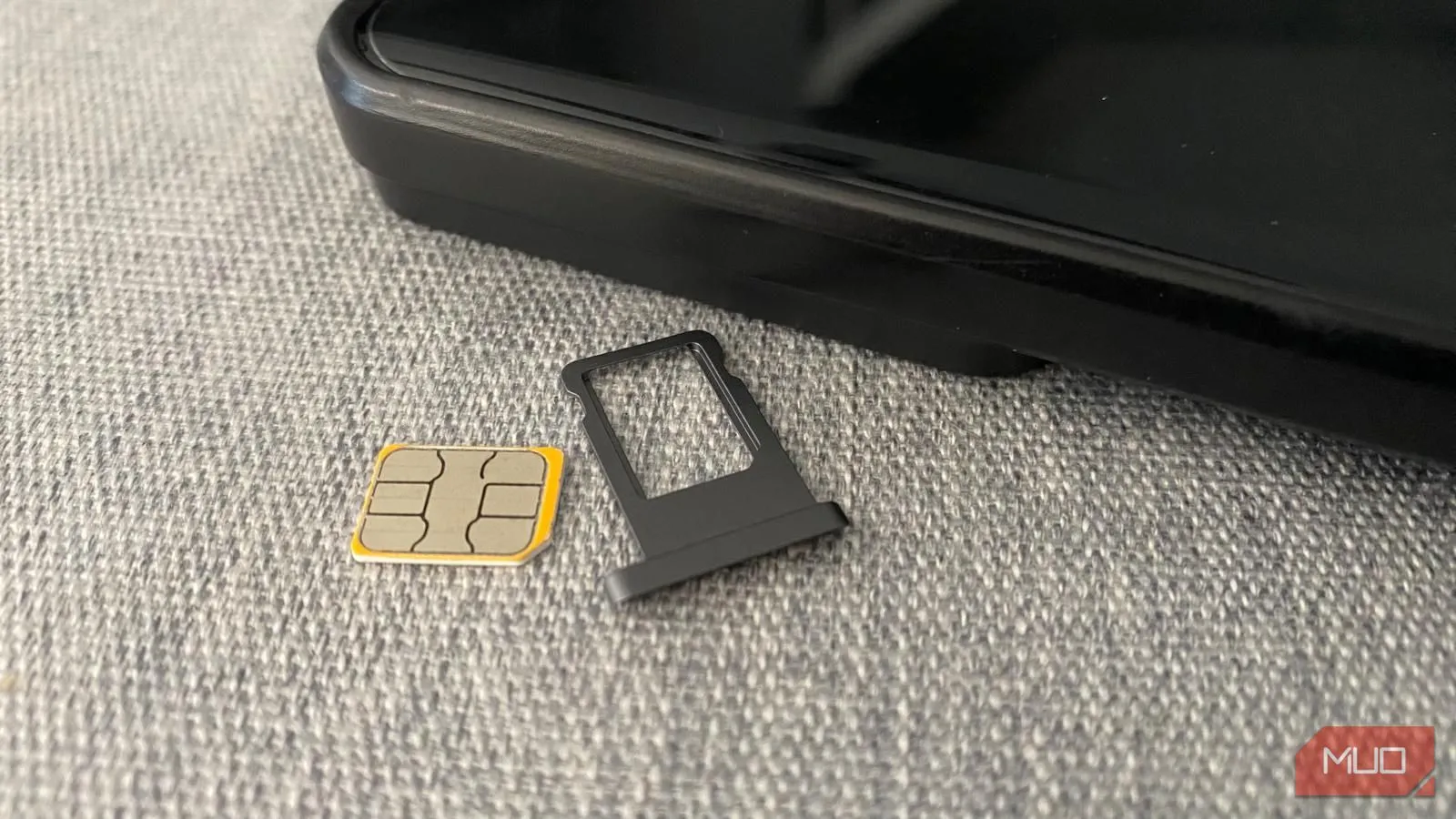 Thẻ SIM vật lý và khay đựng đặt cạnh điện thoại di động trên bàn, minh họa giải pháp kết nối truyền thống.