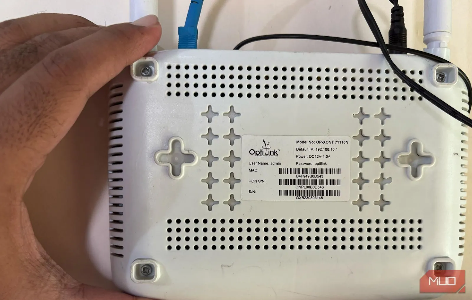 Bàn tay đang cầm một bộ định tuyến (router) và cho thấy mặt sau với các cổng kết nối, minh họa việc truy cập thiết bị.