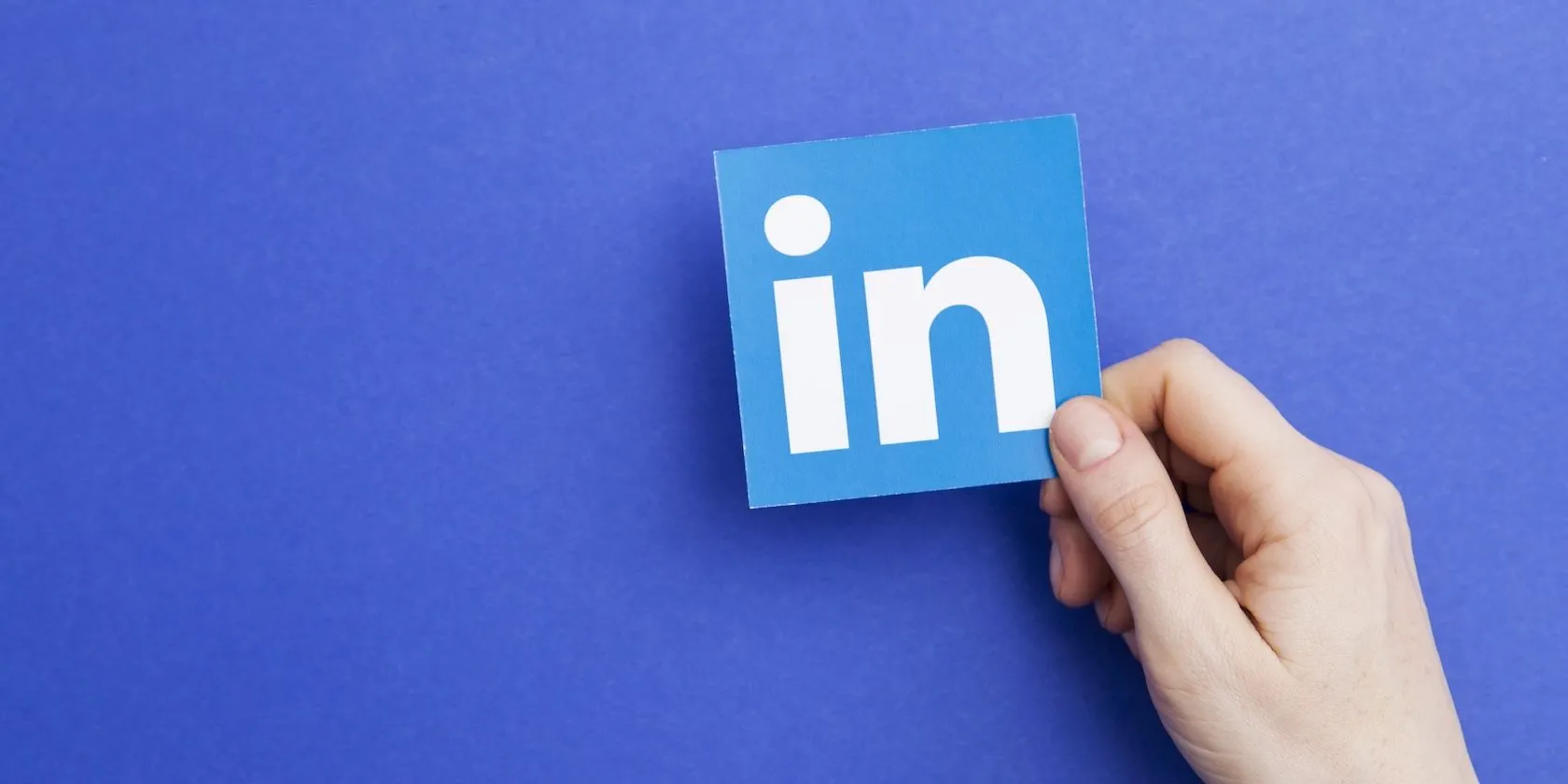 Biểu tượng ứng dụng LinkedIn (chữ &quot;in&quot;) được giữ trên lòng bàn tay, tượng trưng cho mạng lưới kết nối chuyên nghiệp