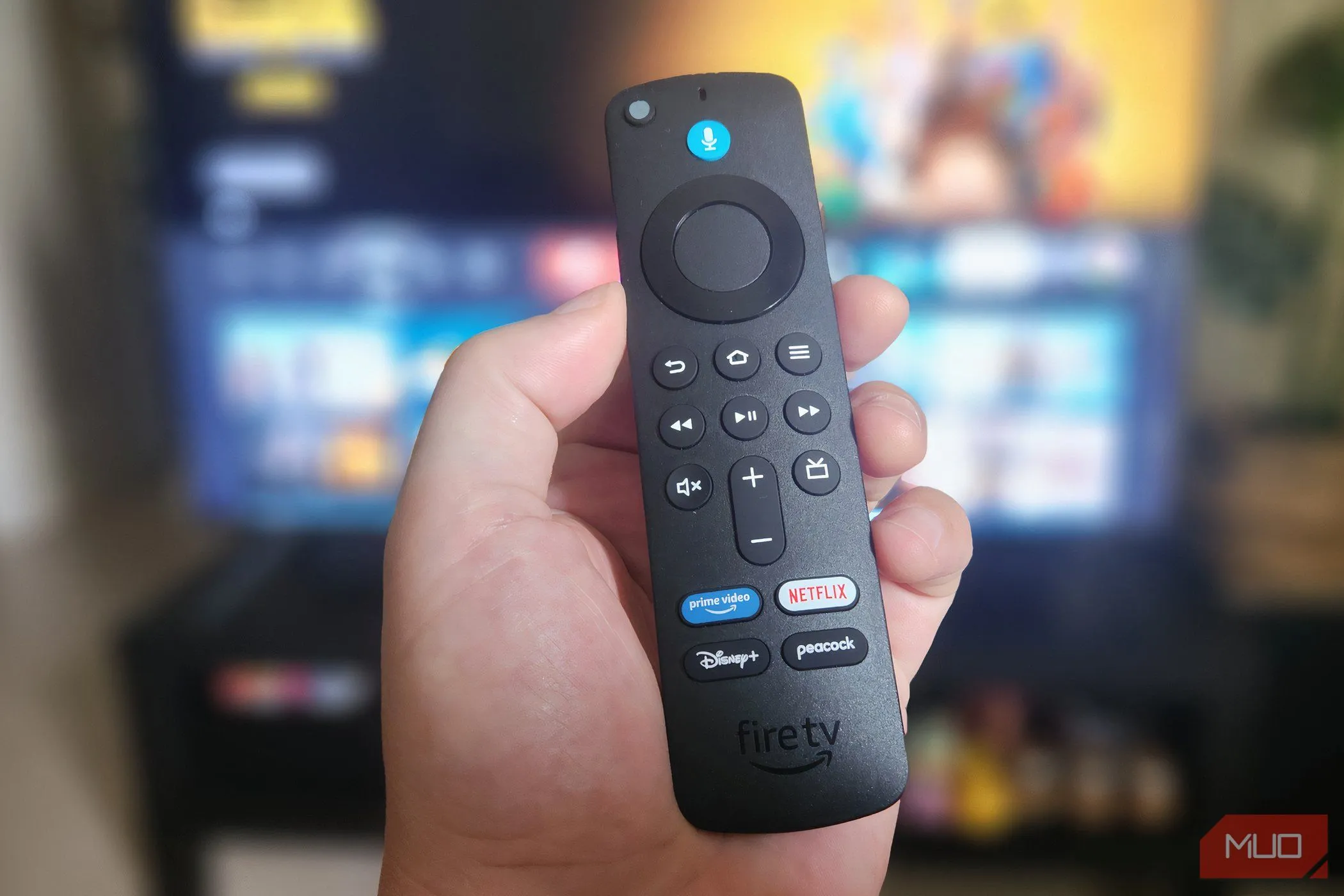 Chiếc điều khiển từ xa Alexa Voice Remote của Fire TV Stick 4K được cầm trên tay, nổi bật nút micro màu xanh.