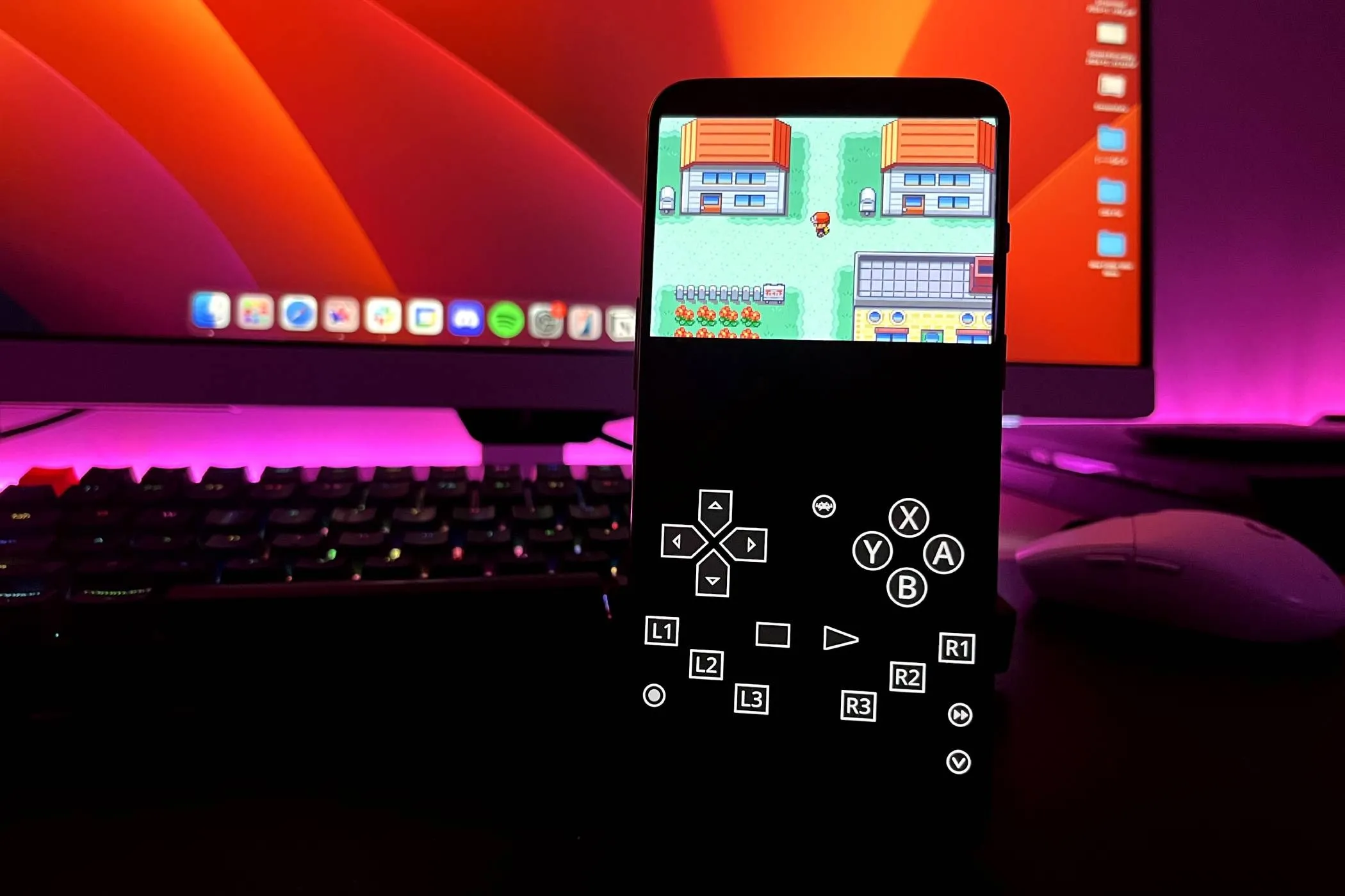 Điện thoại Android đang chạy game Pokémon: Fire Red trên trình giả lập RetroArch, với bàn phím, chuột và màn hình máy tính phía sau