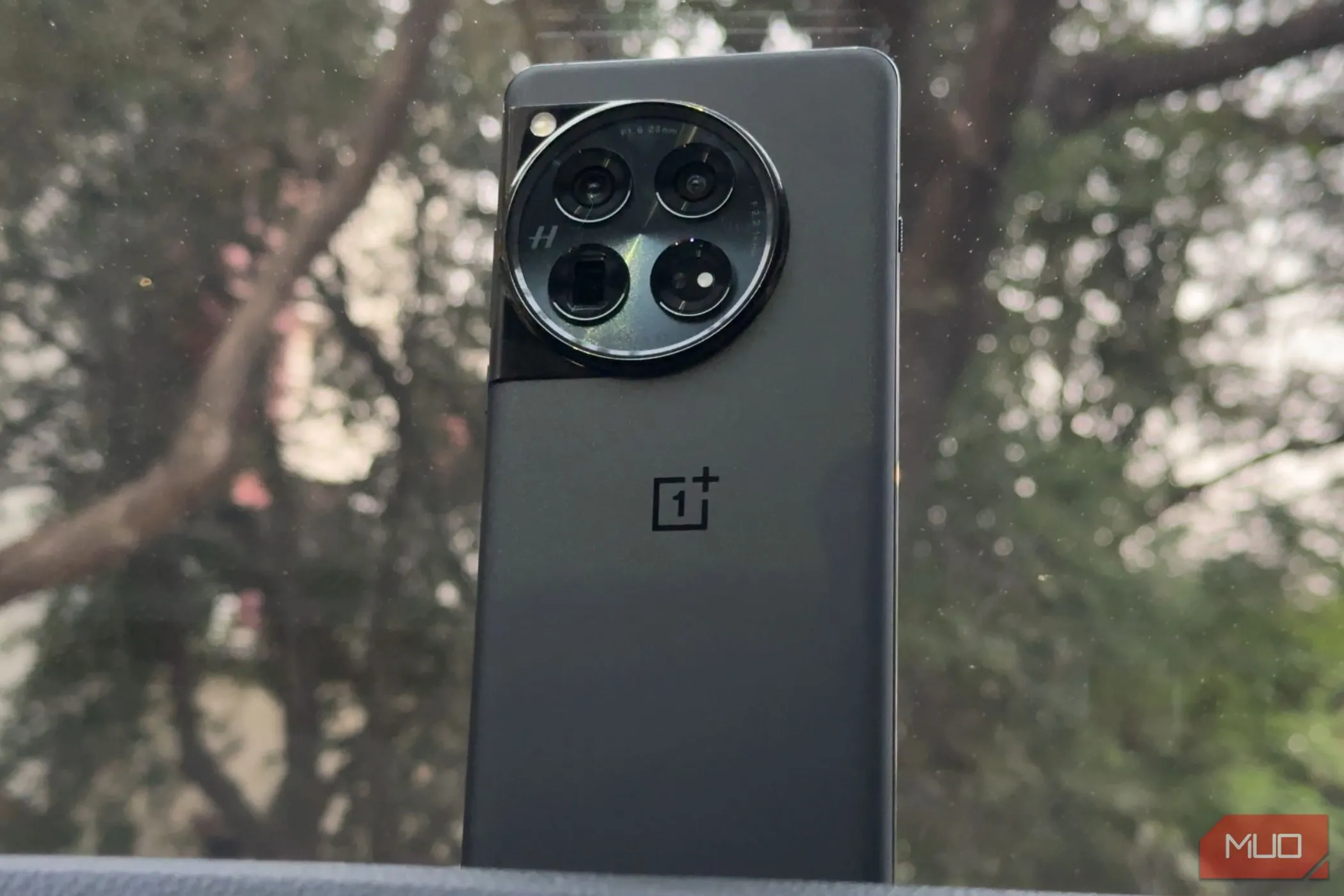 Điện thoại OnePlus 12 màu đen nằm trên táp lô ô tô, thể hiện vẻ ngoài cao cấp và bền bỉ
