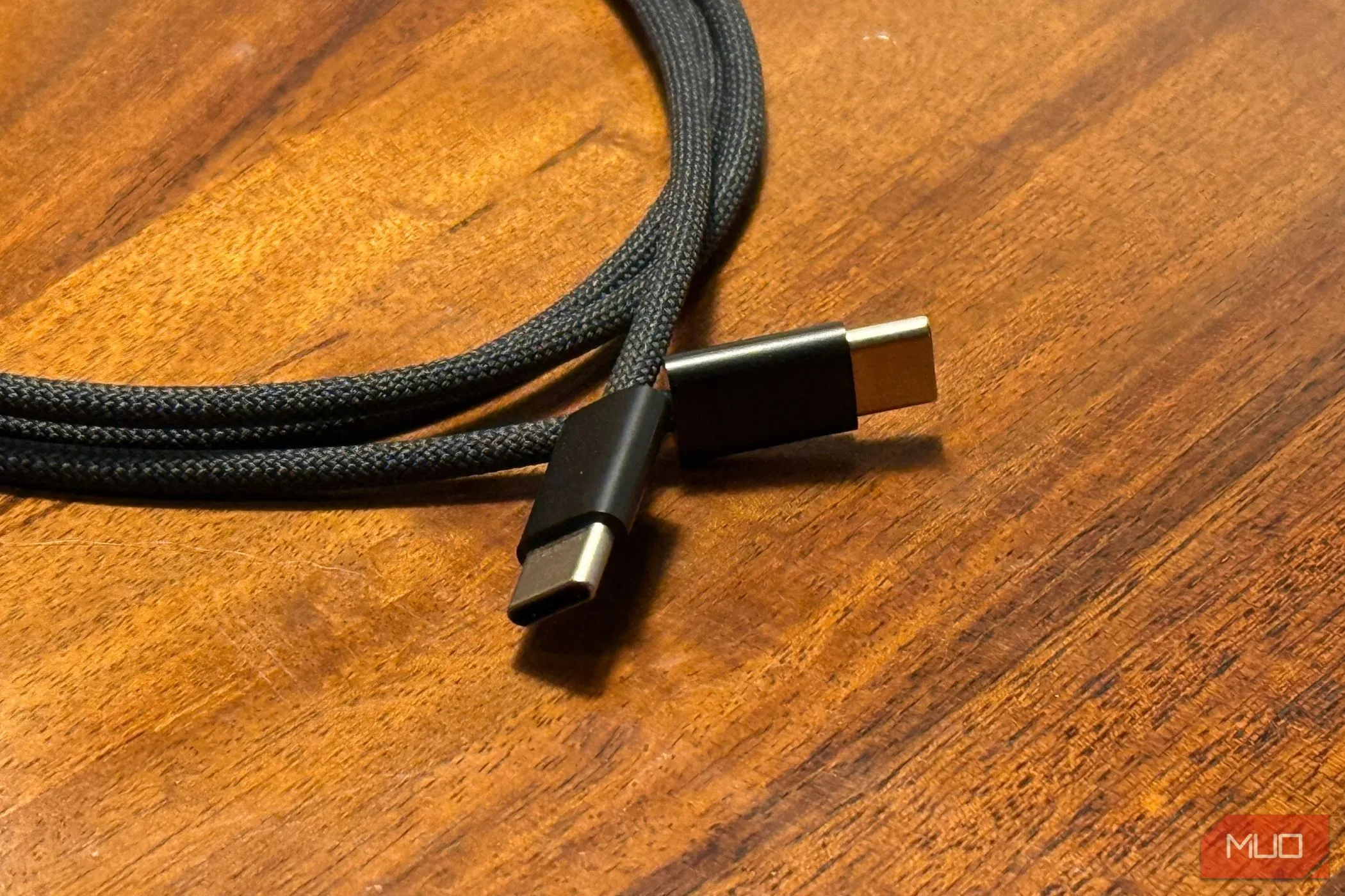 Hai đầu nối của cáp sạc USB-C sang USB-C đặt trên mặt bàn gỗ, minh họa loại cáp hiện đại dùng cho iPhone 15 trở lên.