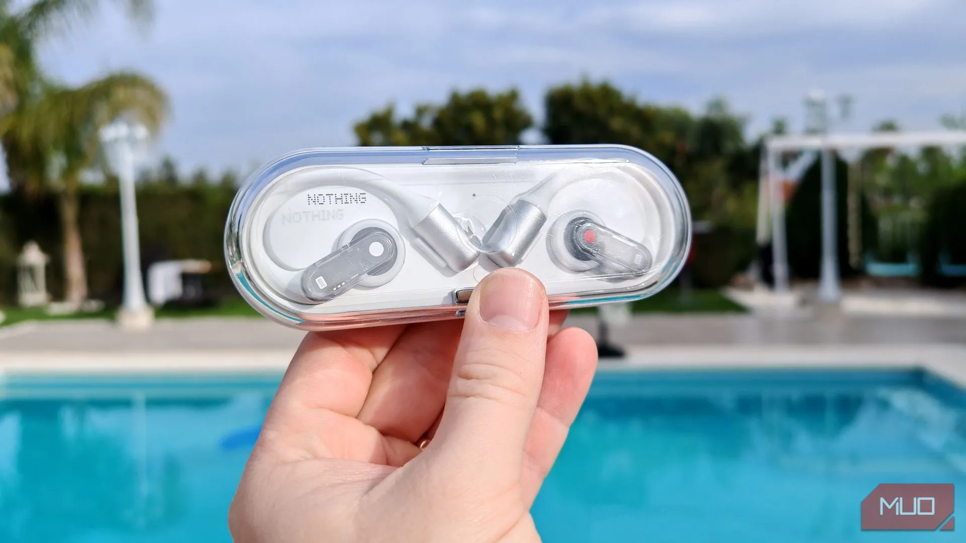 Hộp sạc Nothing Ear (open) mỏng nhẹ được cầm trên tay ở ngoài trời, tôn lên thiết kế trong suốt đặc trưng.