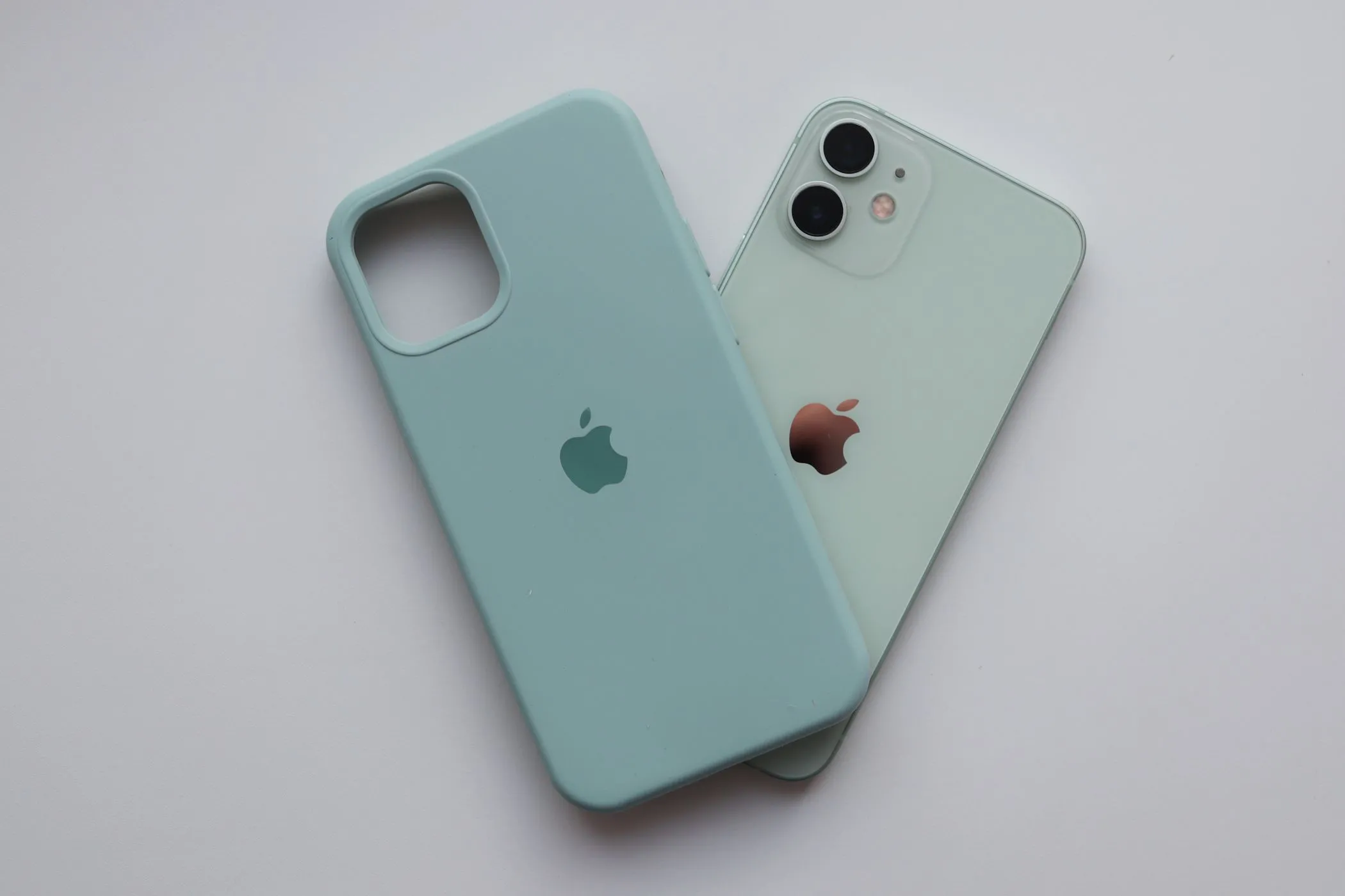 iPhone 12 màu xanh lá pastel đặt cạnh ốp lưng Silicone Apple
