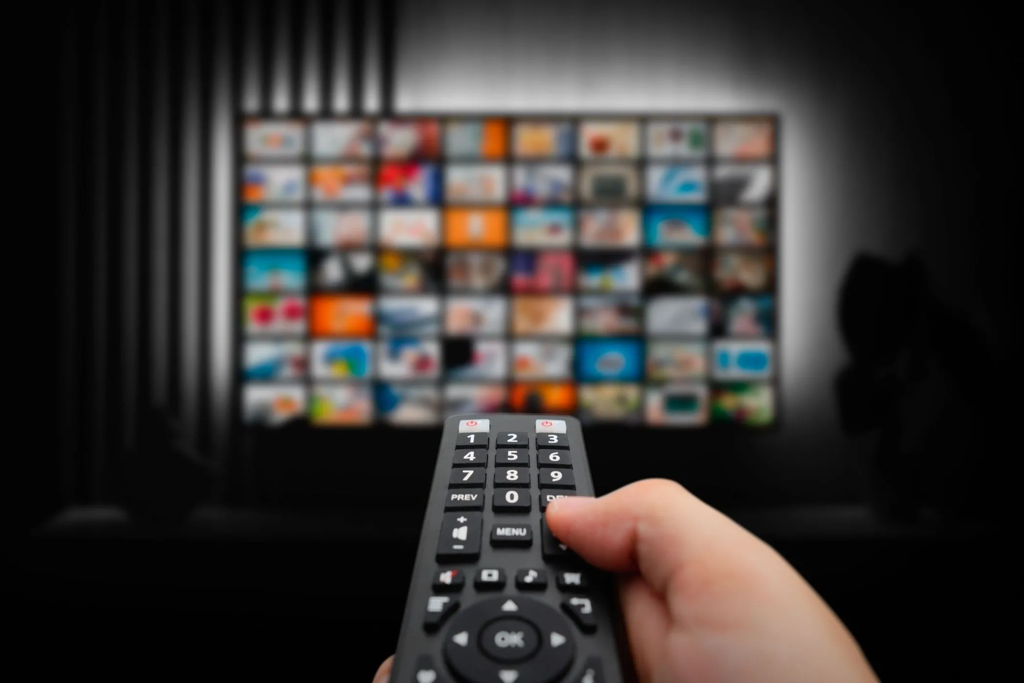 Một chiếc điều khiển từ xa hướng về màn hình TV đang hiển thị giao diện dịch vụ truyền phát, minh họa trải nghiệm xem nội dung số qua internet.