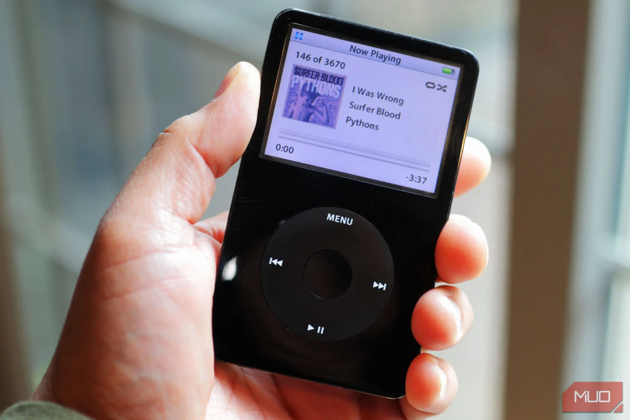 Một chiếc iPod Classic đen trong tay, đại diện cho kỷ nguyên máy nghe nhạc MP3 đã bị smartphone thay thế bằng ứng dụng streaming nhạc