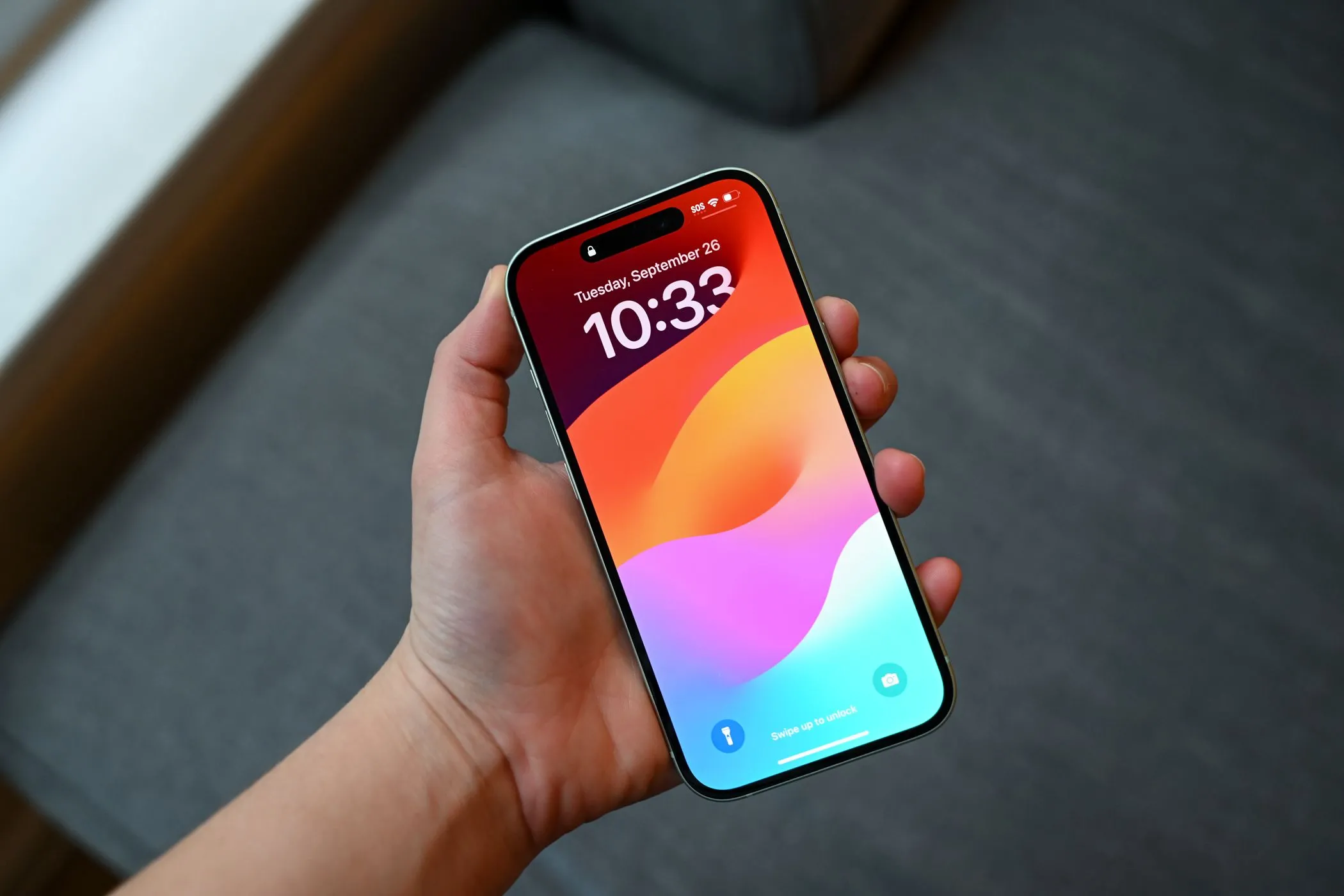 Một người đang cầm chiếc iPhone có màn hình bật sáng, minh họa khả năng che giấu vết xước của miếng dán chống nhìn trộm