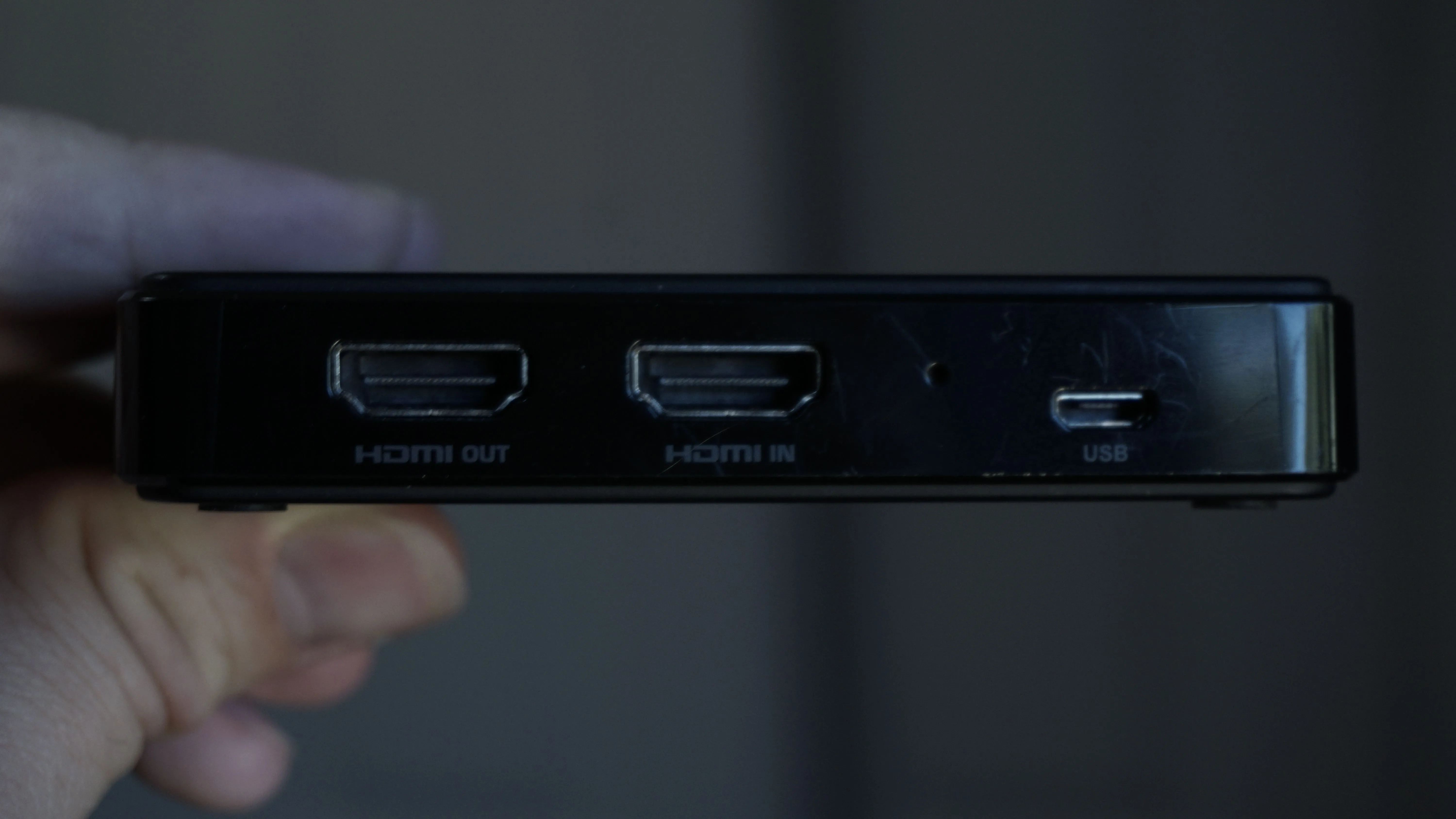Một người đang cầm thẻ ghi hình HDMI và chỉ vào các cổng HDMI vào/ra cùng cổng USB của thiết bị