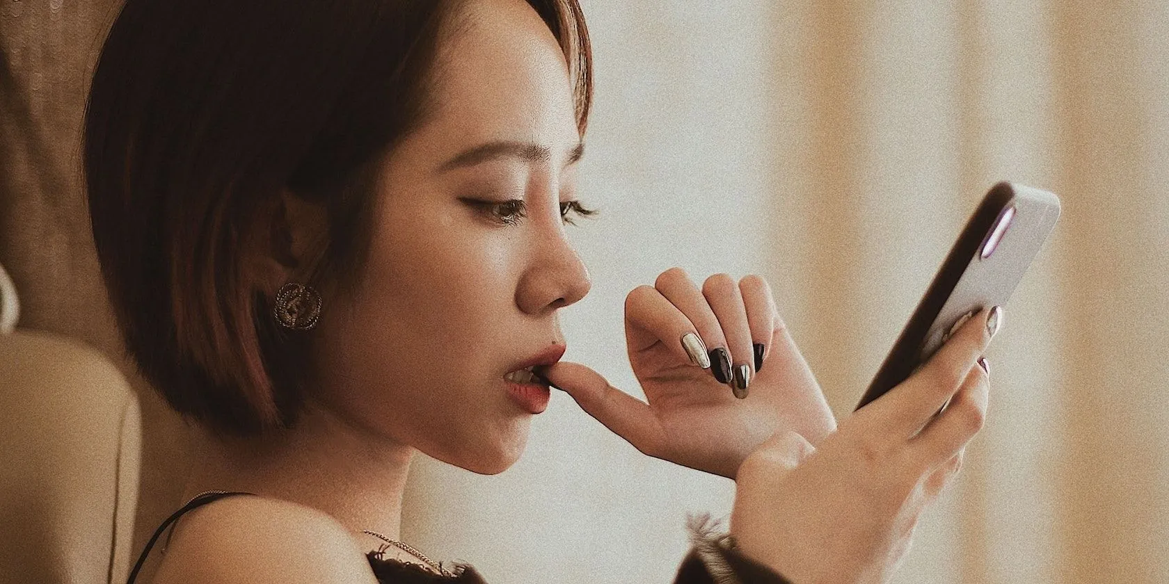 Một người phụ nữ đang nhìn vào điện thoại thông minh với vẻ lo lắng, suy tư về vấn đề bảo mật dữ liệu cá nhân.