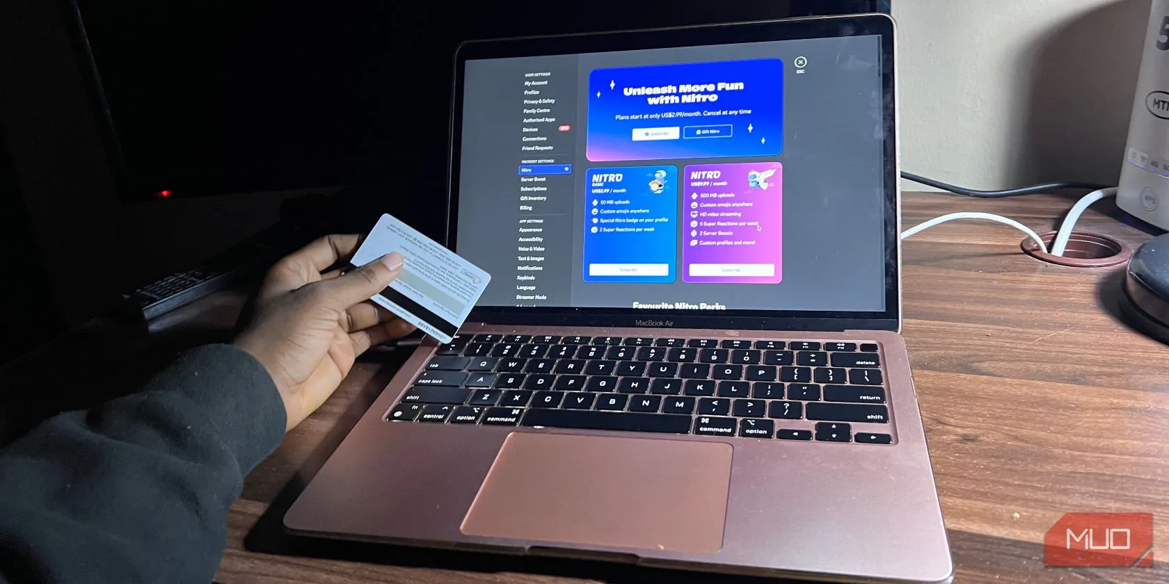 Người đàn ông đang cầm thẻ Discord Nitro trên màn hình MacBook Air, thể hiện chi tiết gói Nitro