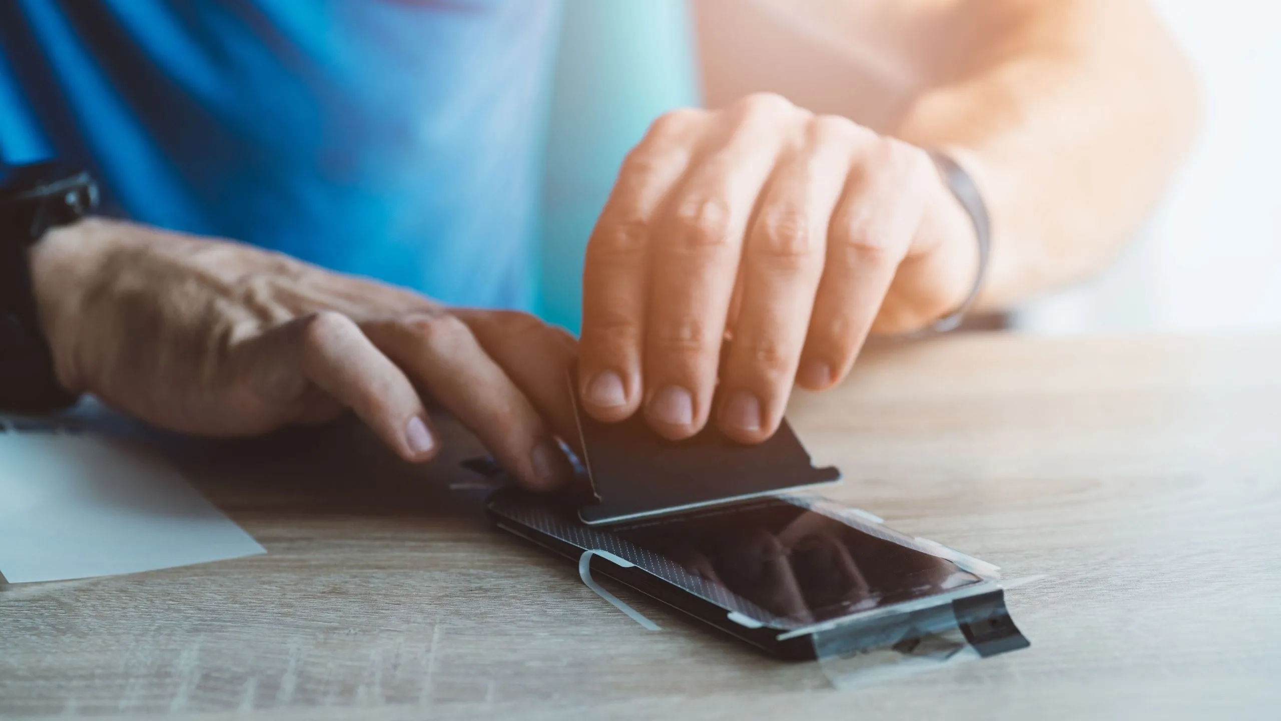 Người đàn ông đang cẩn thận dán miếng bảo vệ màn hình lên điện thoại iPhone.