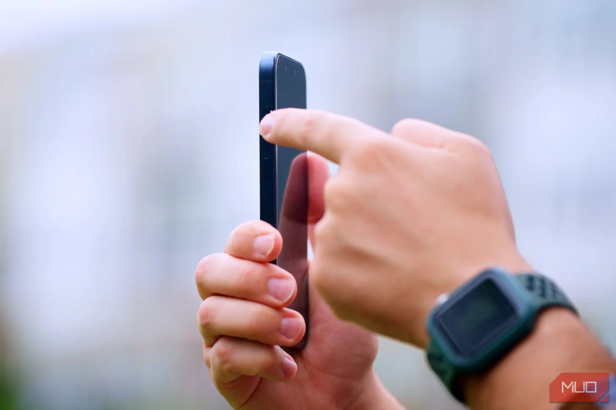Người đàn ông sử dụng ngón trỏ nhấn Nút Hành Động (Action Button) trên cạnh bên của iPhone 15 Pro, minh họa khả năng tùy chỉnh phím cứng