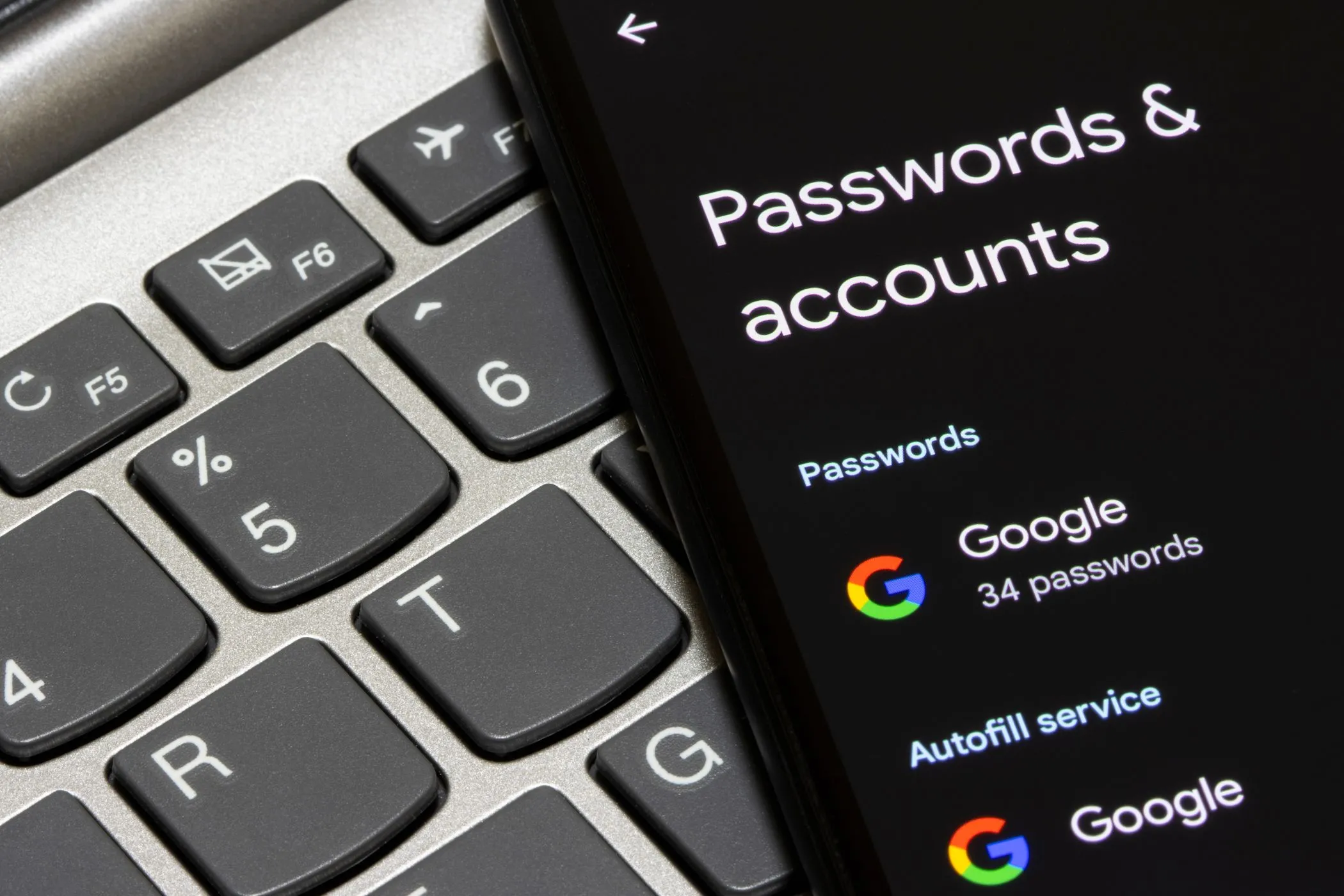 Người dùng kiểm tra tài khoản Google trên điện thoại thông minh cạnh máy tính xách tay, minh họa việc quản lý thông tin cá nhân