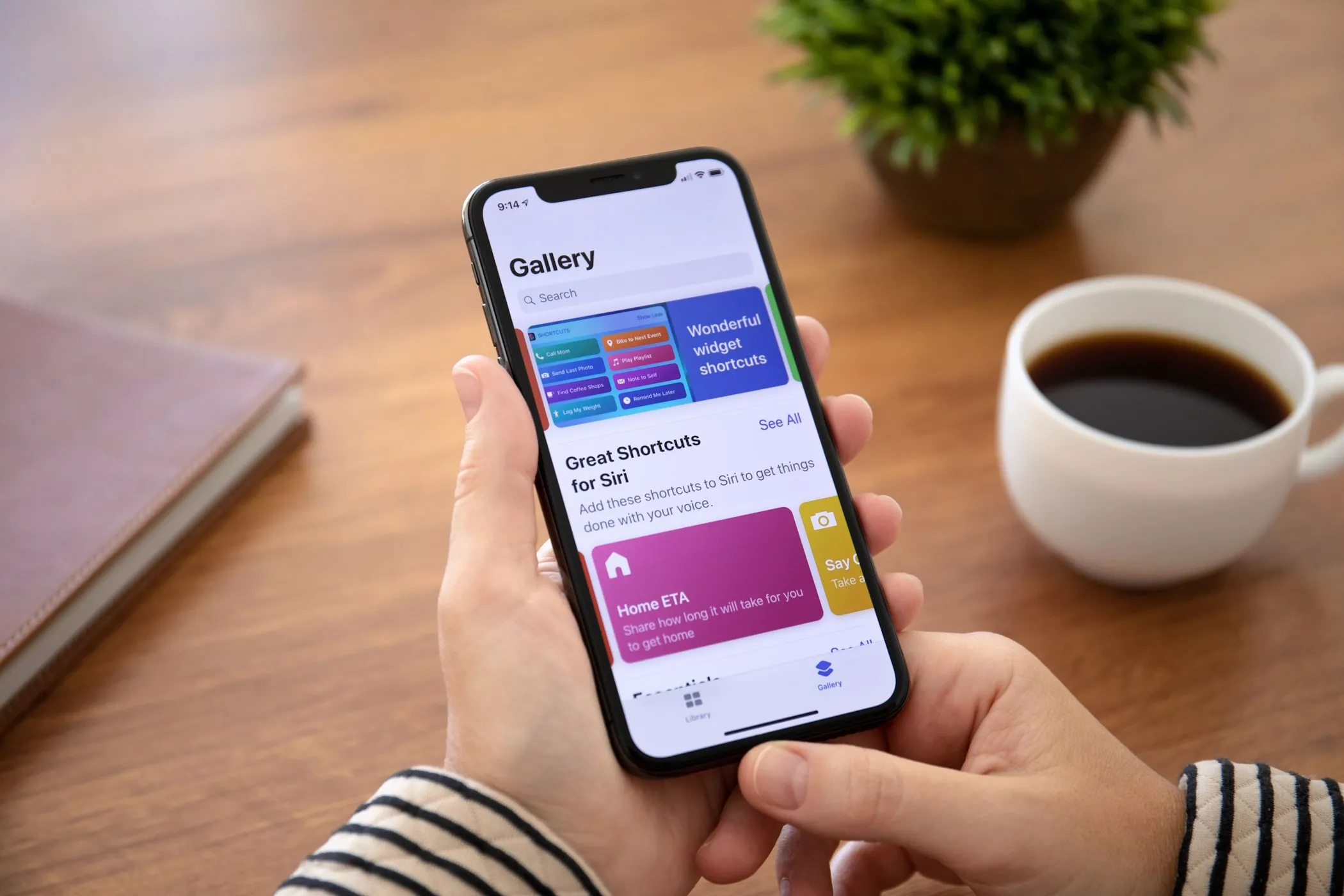 Người phụ nữ đang cầm iPhone hiển thị giao diện Gallery trong ứng dụng Phím tắt iOS, minh họa kho phím tắt có sẵn.