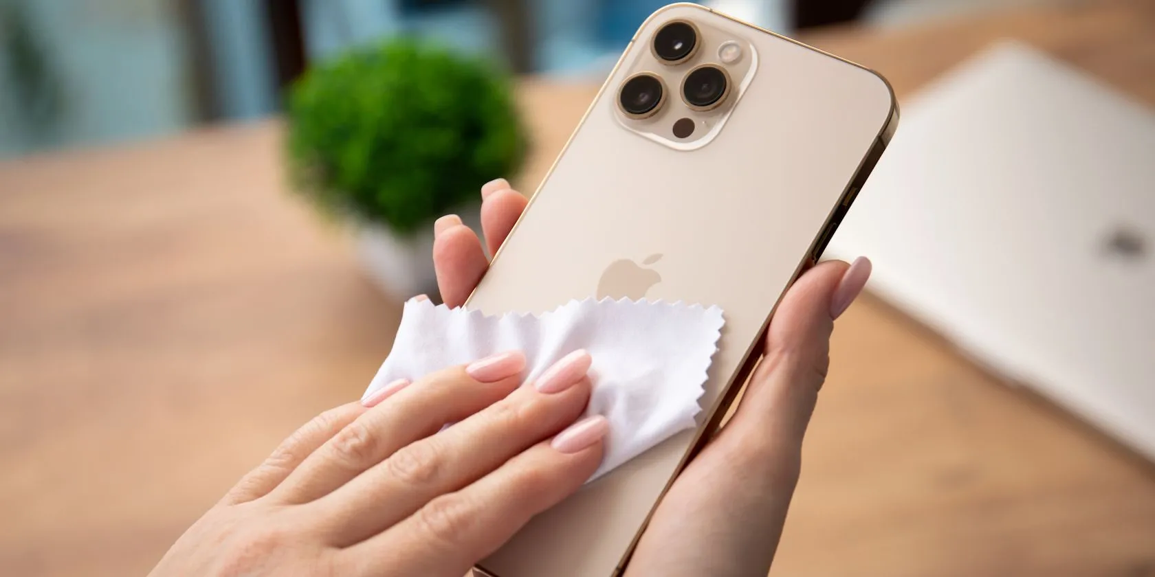 Người phụ nữ đang nhẹ nhàng vệ sinh màn hình iPhone của mình bằng vải microfiber sạch.