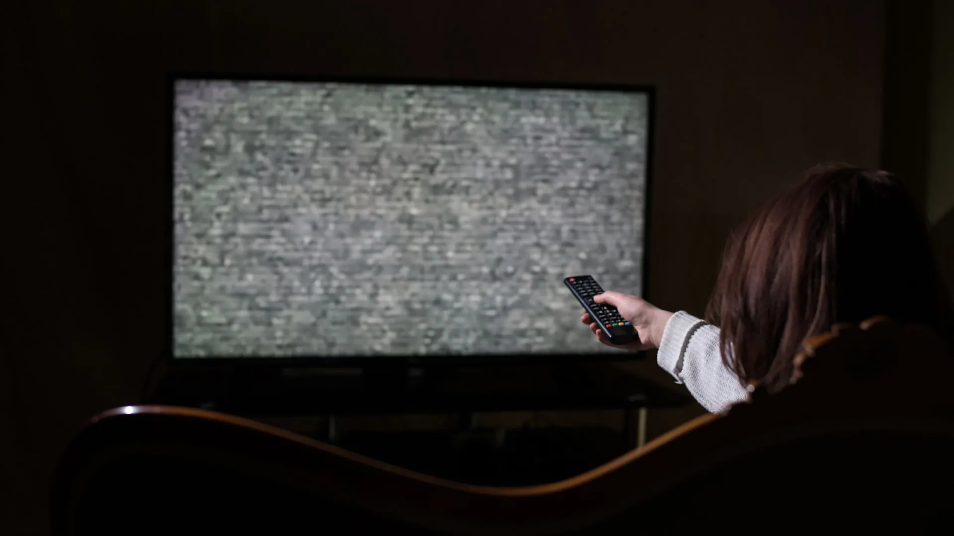 người phụ nữ dùng remote Smart TV với chiếc TV hỏng