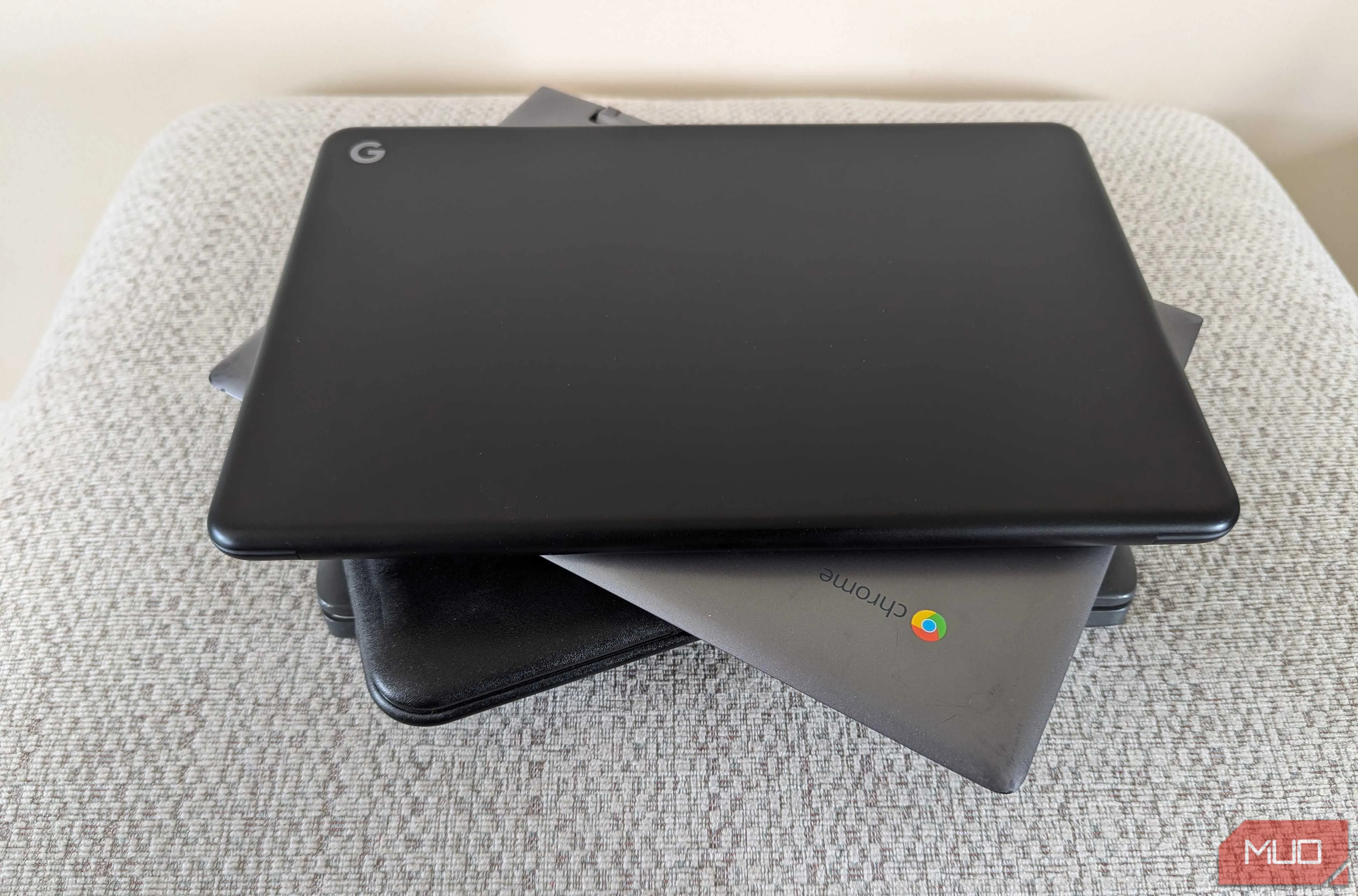 Nhiều chiếc Chromebook được xếp chồng lên nhau gọn gàng trên một chiếc ghế đẩu nhỏ, thể hiện tính di động và sự đa dạng của dòng laptop này.
